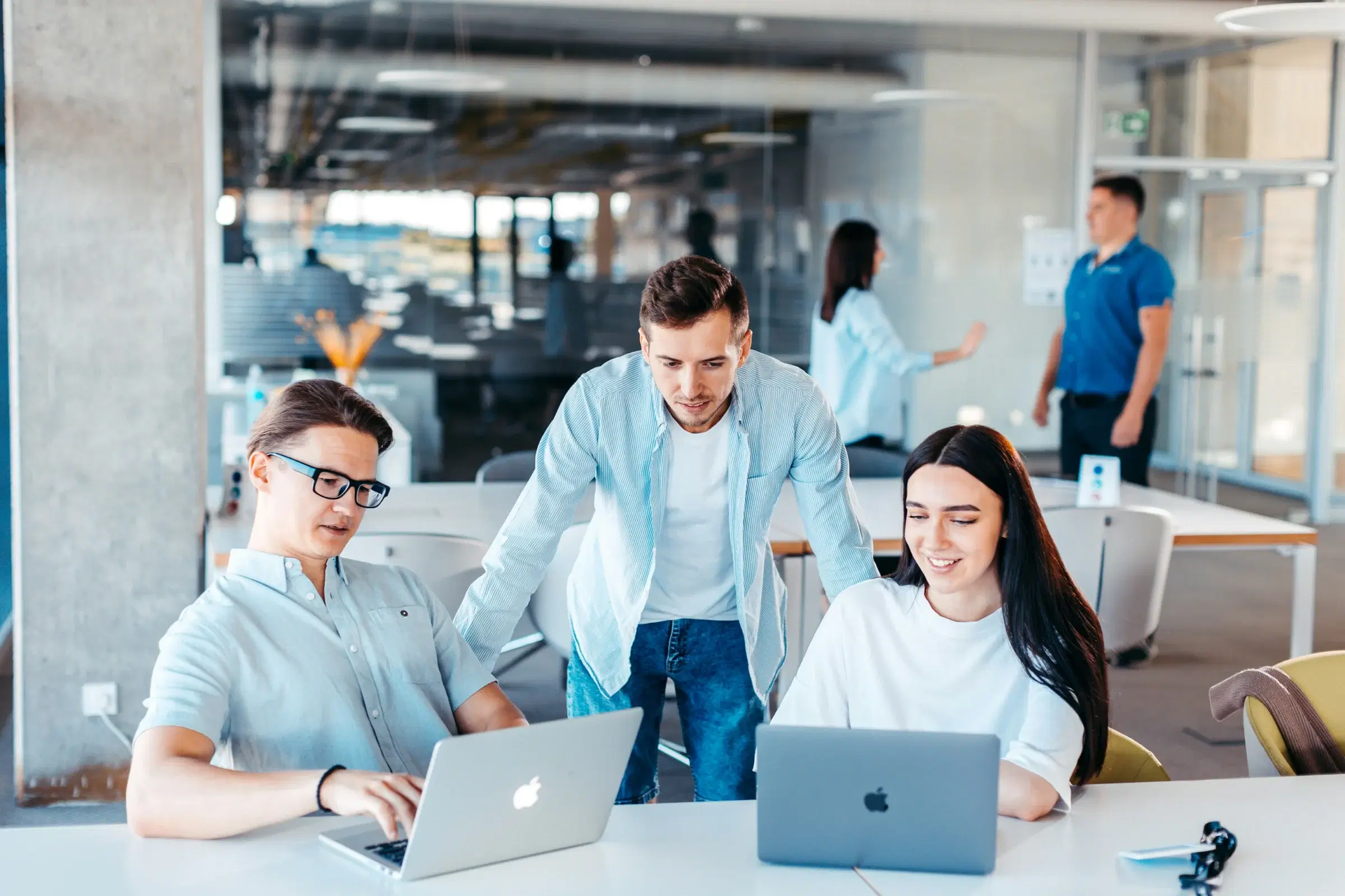Colleagues working together at laptops in a bright open-plan office